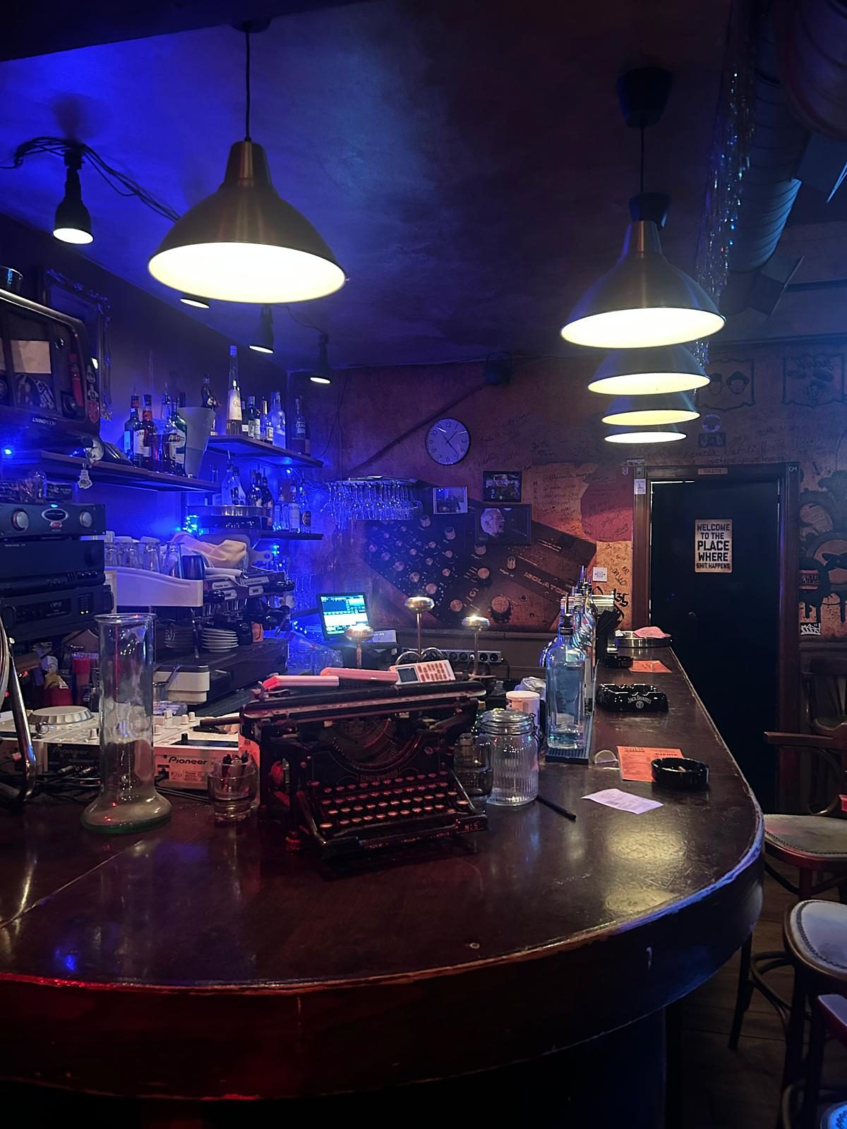 The curved bar counter at Dolce Vita with its old typewriter and bottles under warm pendant lights