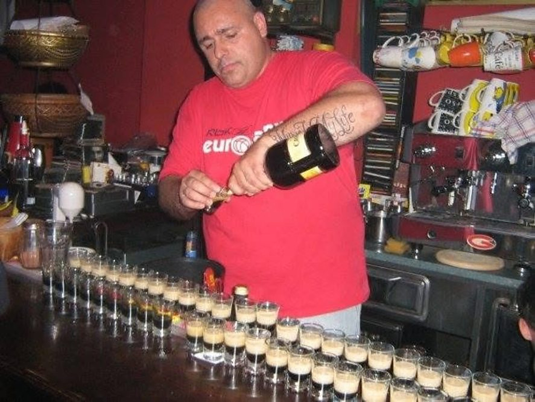Bartender pouring a long row of layered shots
