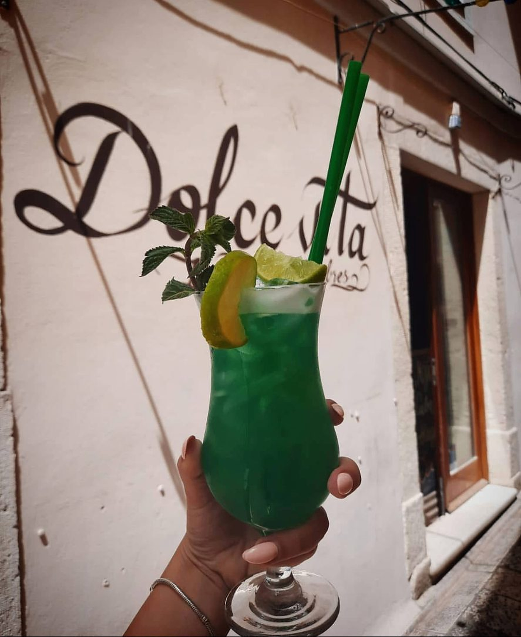 A cocktail held in front of the Dolce Vita logo