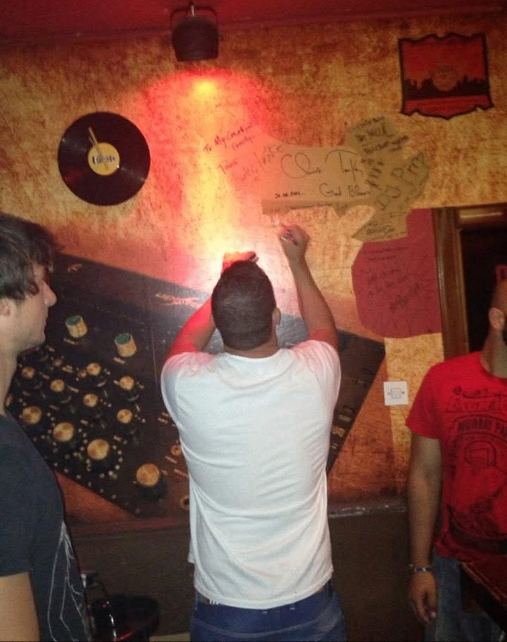 A guest signing the bar's wall of signatures