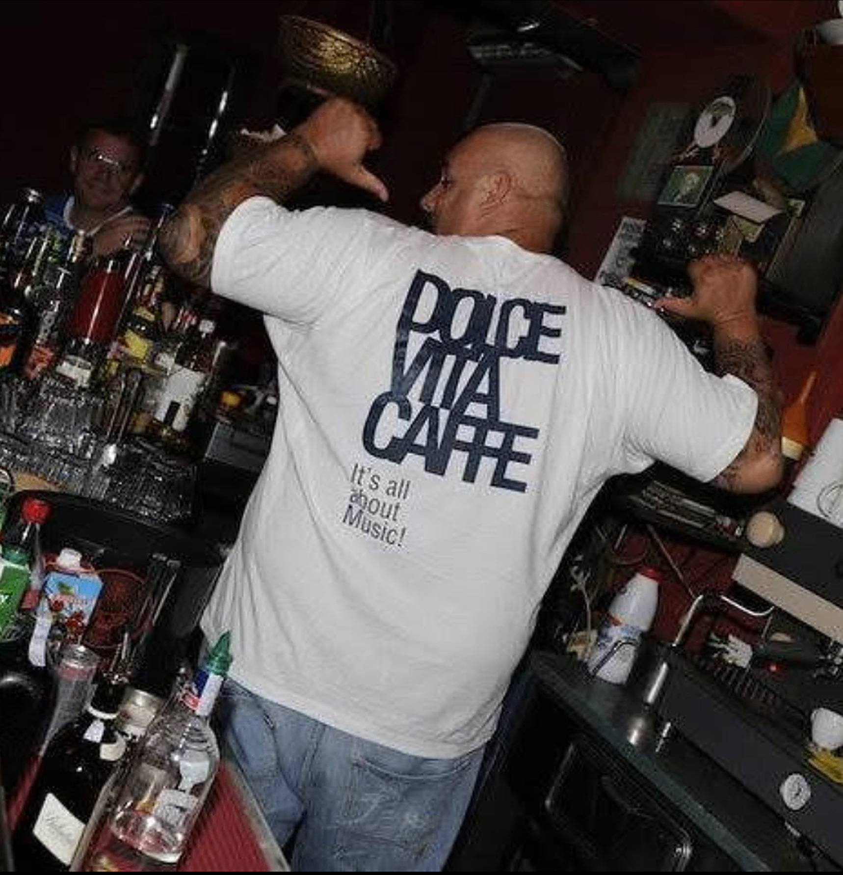 Bartender behind the counter wearing the Dolce Vita Caffe shirt reading It's all about Music!